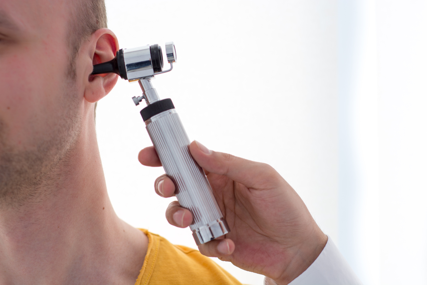 Doctor examining patients ear in doctors office